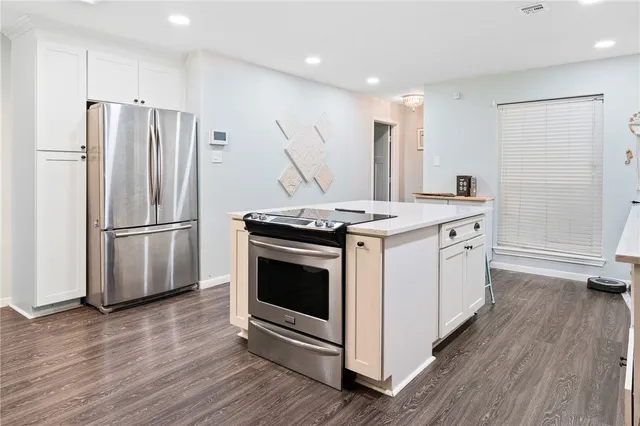 a kitchen with stainless steel appliances a stove a refrigerator and a wooden floor