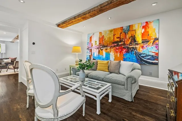 a living room with furniture a rug and a wall painting