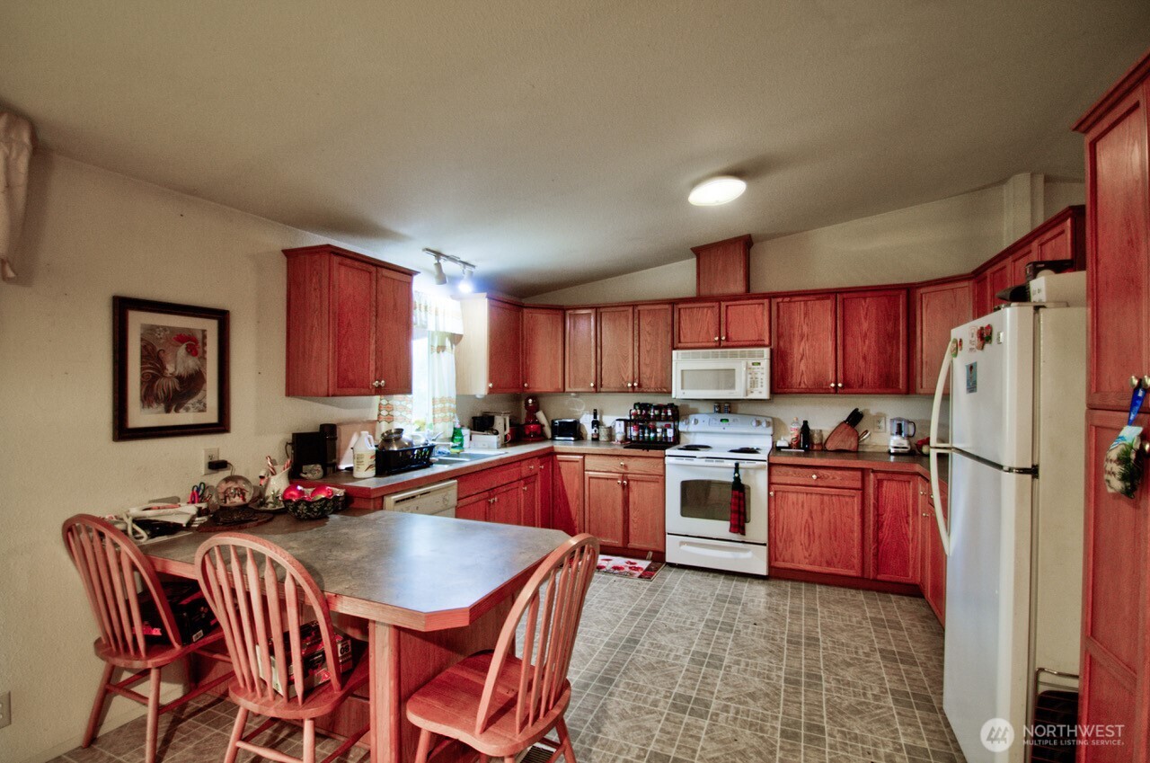 236 Tryon Road Onalaska, WA 98570 - Photo 6 of 40 a kitchen with stainless steel appliances granite countertop a refrigerator a sink dishwasher a stove a dining table and chairs with wooden floor