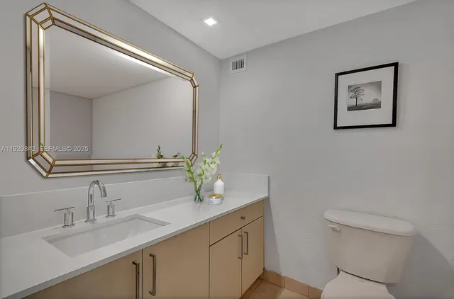a bathroom with a granite countertop sink mirror and toilet