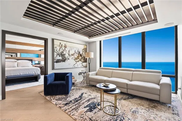 a living room with furniture a rug potted plant and a large window