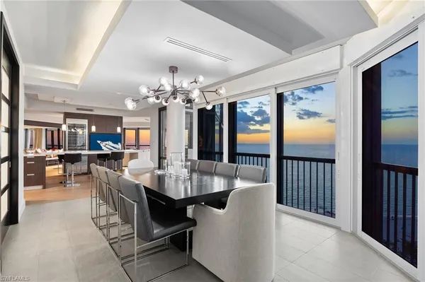a dining room with furniture a chandelier and large window