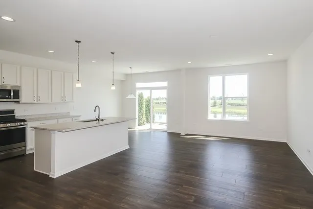 a large kitchen with stainless steel appliances granite countertop a sink a stove a microwave and island with wooden floor