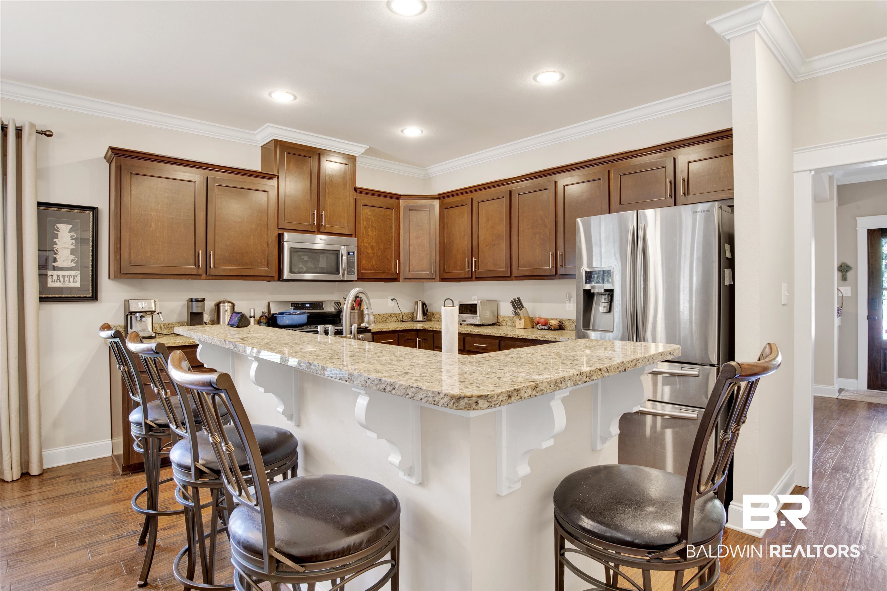360 Scarlett Avenue Fairhope, AL 36532 - Photo 10 of 34 Kitchen featuring light stone countertops, appliances with stainless steel finishes, dark hardwood / wood-style floors, and a breakfast bar
