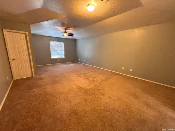 an empty room with a chandelier fan and windows