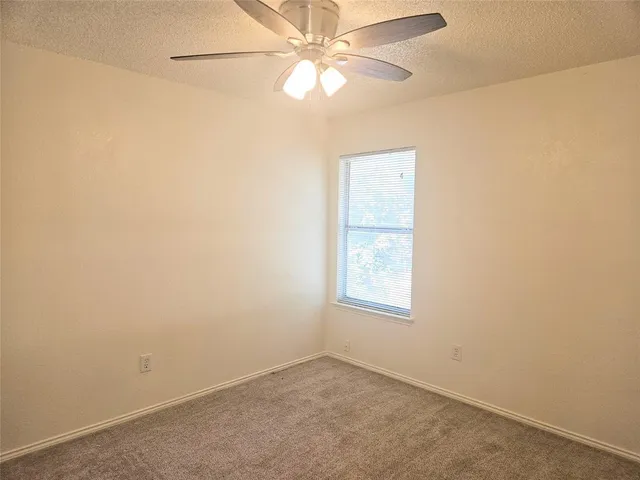 an empty room with a window and a fan