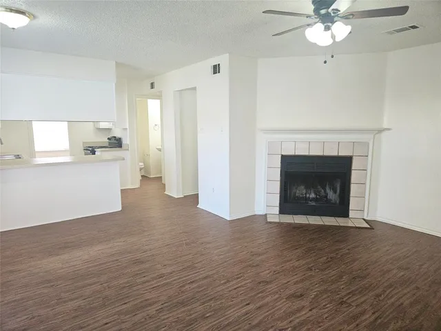 a view of a kitchen with a fireplace a ceiling fan and wooden floor