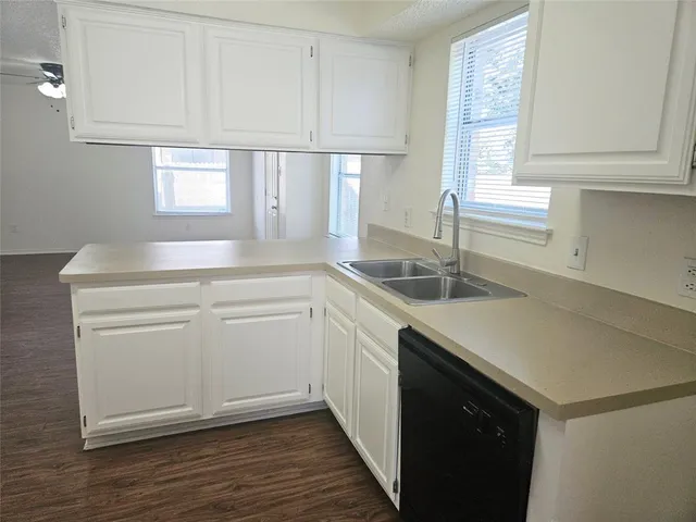 a kitchen with white cabinets appliances a sink and a window