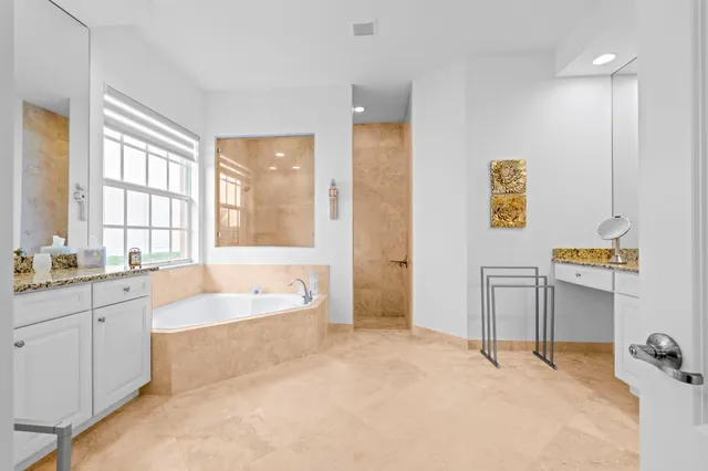 a spacious bathroom with a tub sink shower and mirror