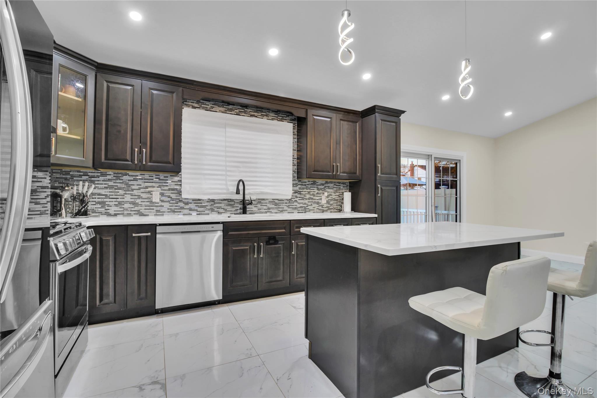 858 Prescott Street Valley Stream, NY 11580 - Photo 11 of 48 Kitchen featuring light marble finish flooring, dark brown cabinets, stainless steel appliances, a breakfast bar, and backsplash