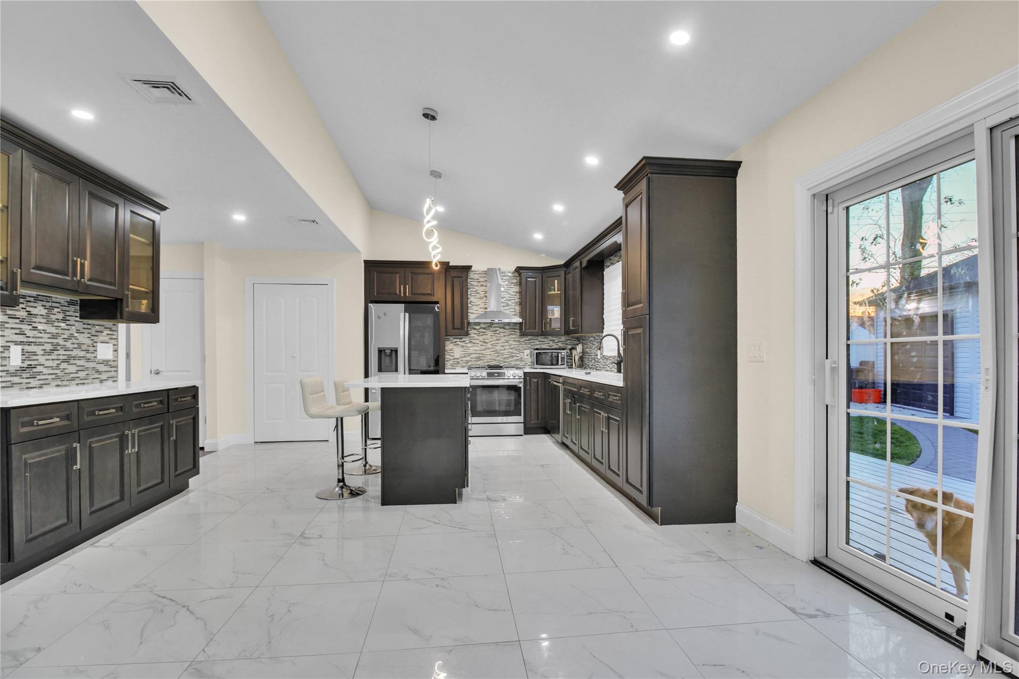 858 Prescott Street Valley Stream, NY 11580 - Photo 13 of 48 Kitchen featuring glass insert cabinets, a kitchen bar, a center island, vaulted ceiling, and light marble finish flooring