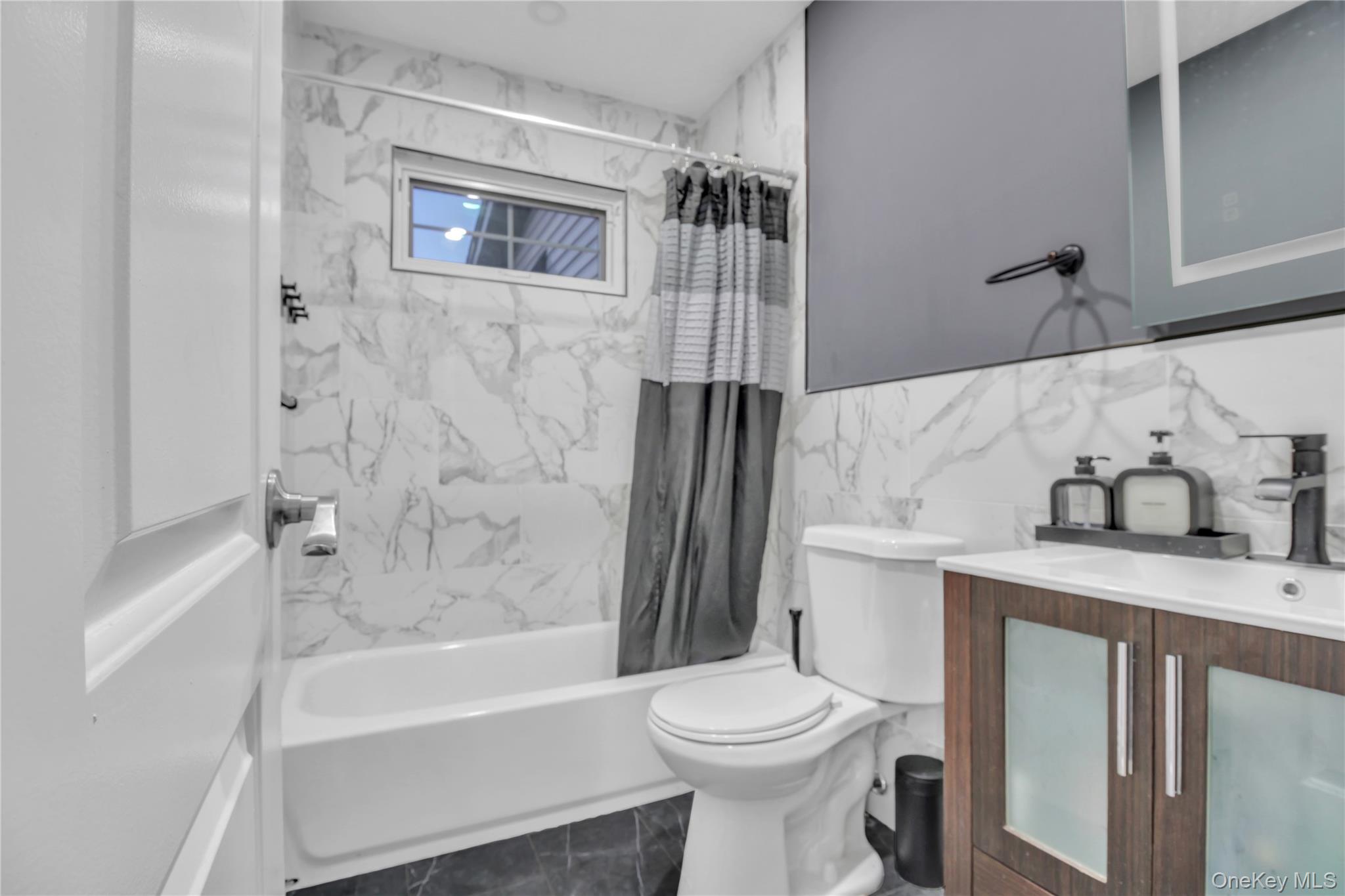 858 Prescott Street Valley Stream, NY 11580 - Photo 15 of 48 Full bathroom with dark marble finish flooring, tile walls, shower / bath combo, vanity, and wainscoting