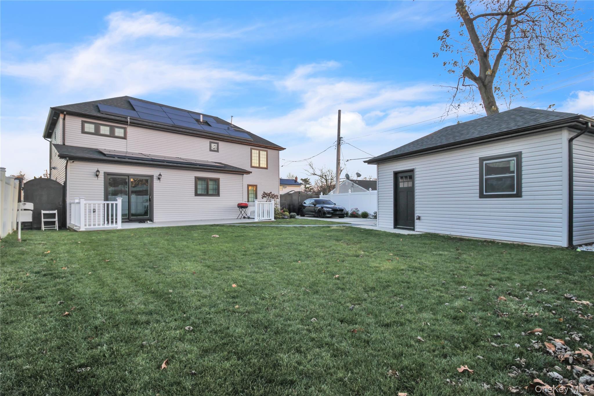 858 Prescott Street Valley Stream, NY 11580 - Photo 42 of 48 Rear view of property featuring solar panels, a fenced backyard, an outdoor structure, and a gate
