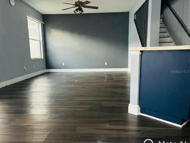 an empty room with wooden floor fan and windows