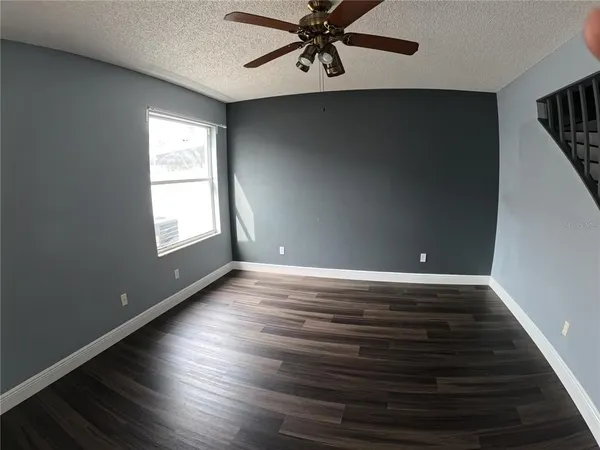 an empty room with wooden floor fan and windows