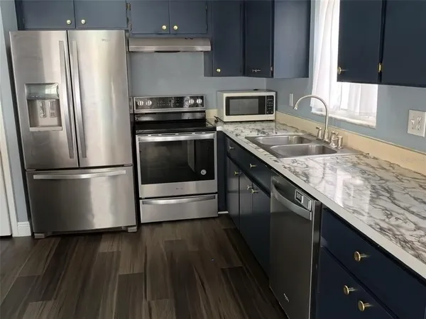 a kitchen with granite countertop a refrigerator stove and sink