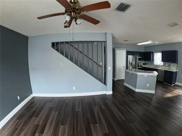 a view of a room with wooden floor a ceiling fan and staircase