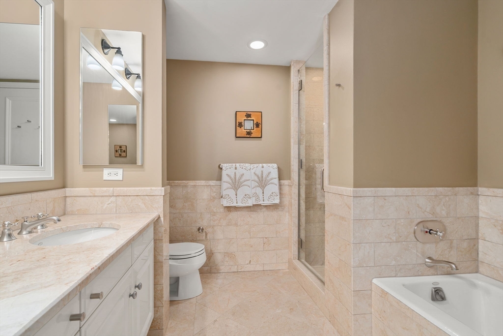 1 Avery Street, Unit 16G Boston, MA 02111 - Photo 12 of 15 a bathroom with a granite countertop sink a toilet a mirror a vanity and shower