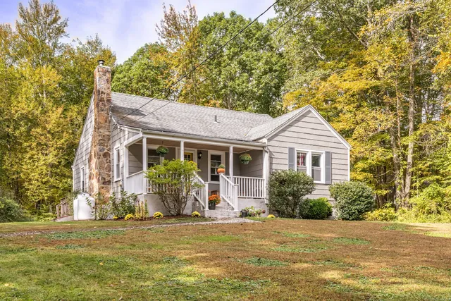 a front view of house with yard and trees in the background