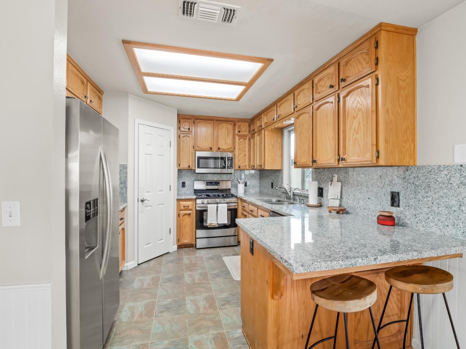 31173 Moccassin Way Coarsegold, CA 93614 - Photo 16 of 48 a kitchen with stainless steel appliances granite countertop a sink refrigerator and cabinets