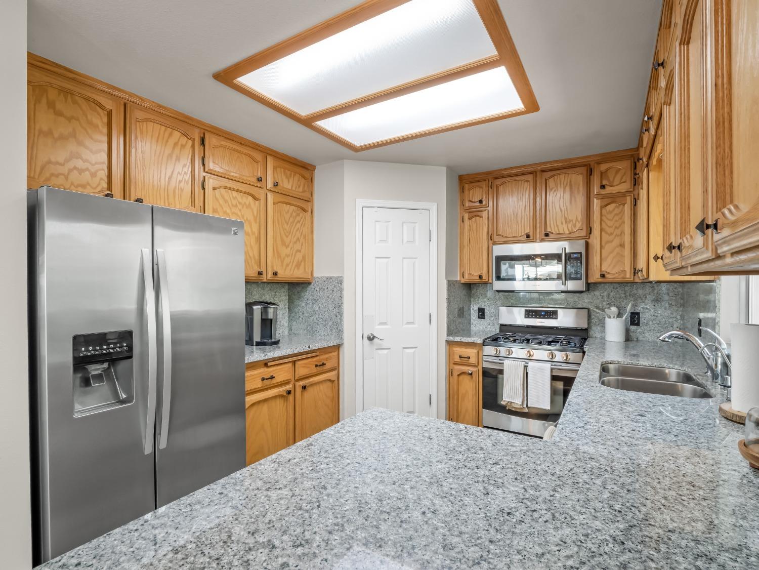 31173 Moccassin Way Coarsegold, CA 93614 - Photo 17 of 48 a kitchen with stainless steel appliances granite countertop a refrigerator a stove top oven a sink and dishwasher