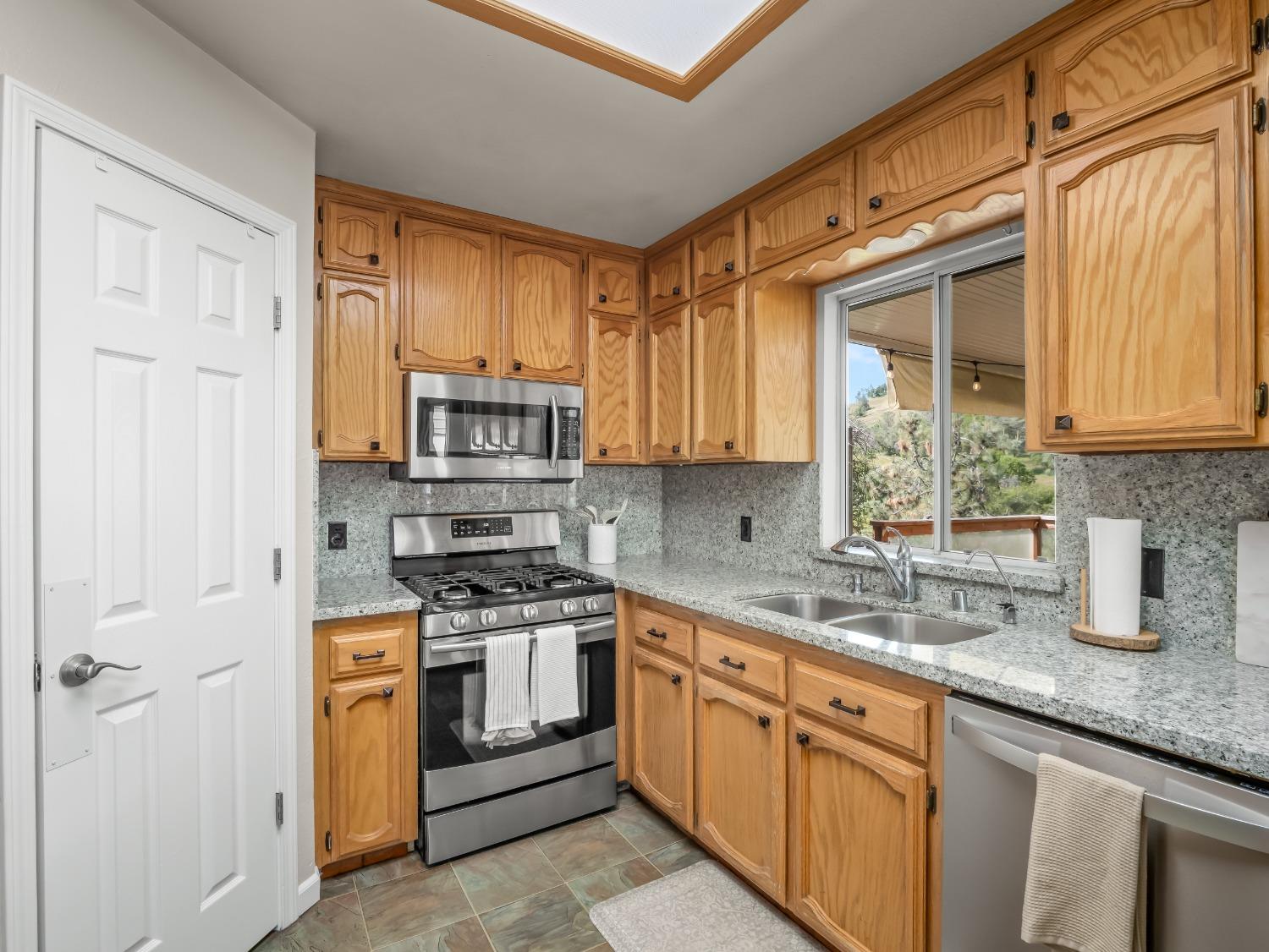 31173 Moccassin Way Coarsegold, CA 93614 - Photo 18 of 48 a kitchen with stainless steel appliances granite countertop a stove a sink and a microwave