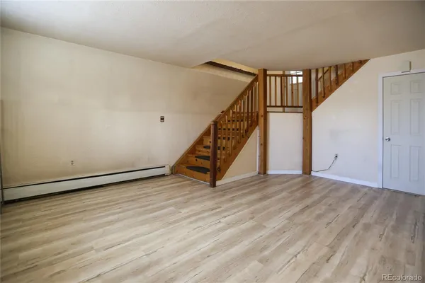 a view of an empty room with wooden floor and stairs