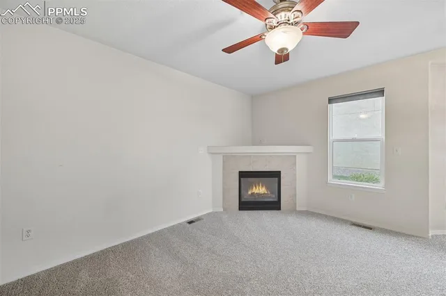 a view of an empty room with wooden floor and a fireplace