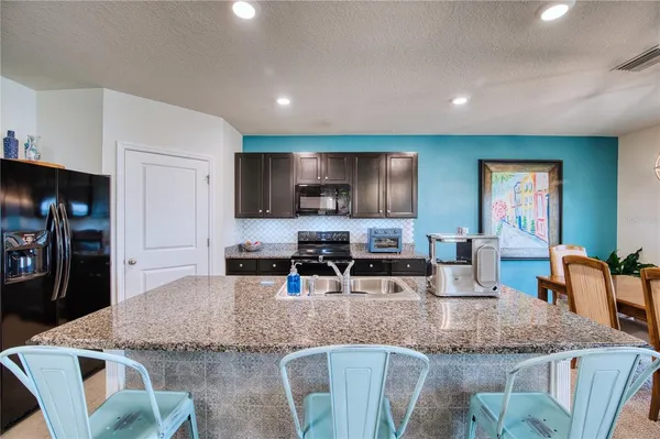 a kitchen with granite countertop kitchen island a table and chairs in it