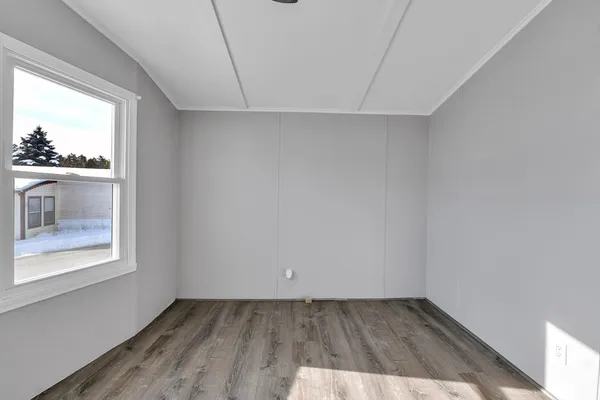 a view of an empty room with window and wooden floor