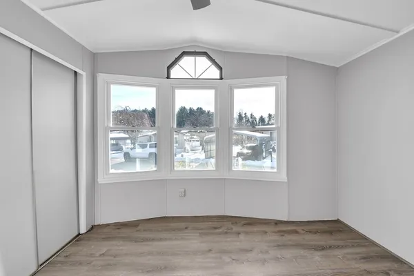a view of an empty room with a window and wooden floor