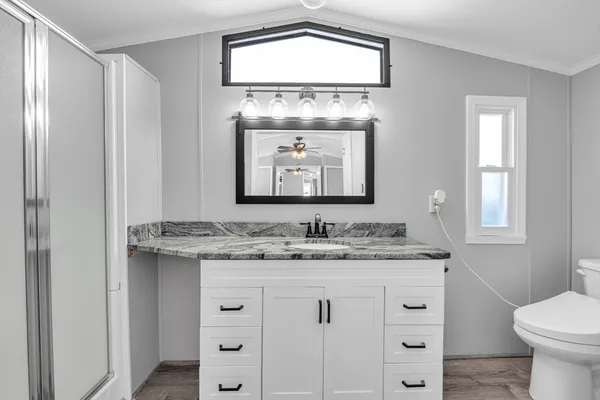 a bathroom with a granite countertop sink vanity mirror and toilet
