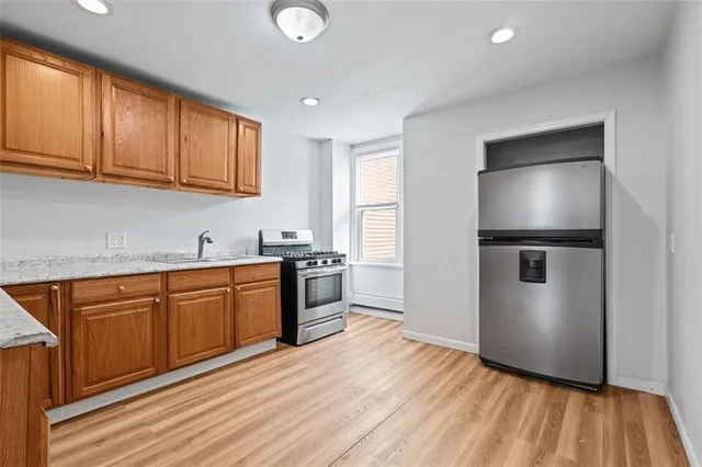 a kitchen with stainless steel appliances granite countertop a refrigerator a sink dishwasher and wooden cabinets with wooden floor