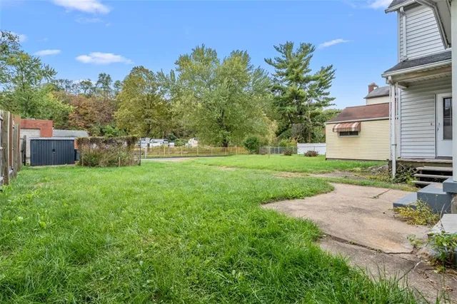 a view of a house with backyard and a tree