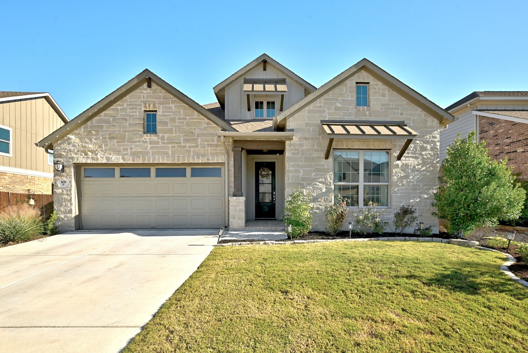 108 Leon Loop Liberty Hill, TX 78642 - Photo 1 of 39 View of front facade featuring stone siding, a standing seam roof, concrete driveway, a front yard, and a metal roof