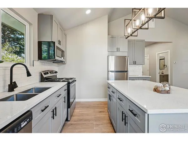 a view living room with stainless steel appliances wooden floor large window and kitchen view