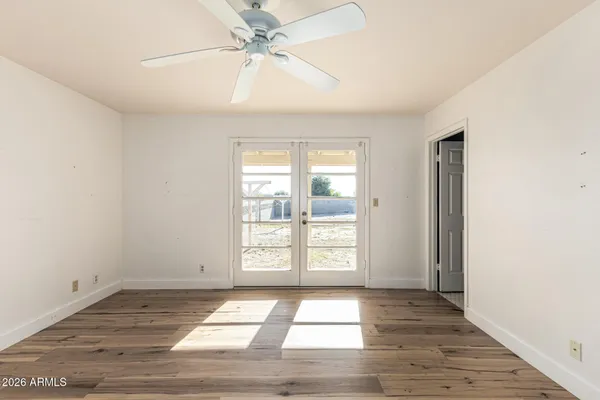 an empty room with wooden floor fan and windows