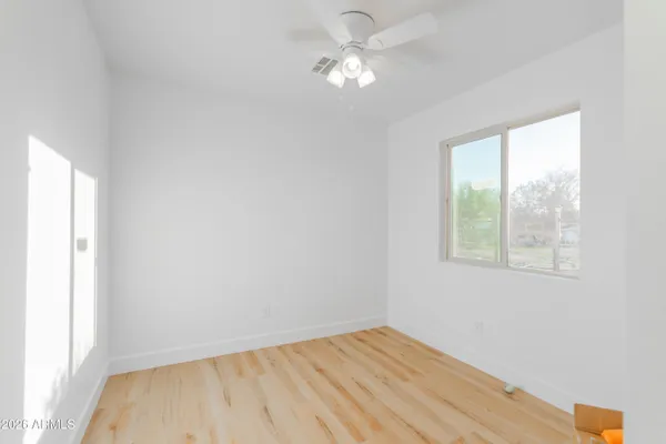 an empty room with a window and a ceiling fan