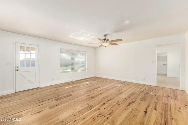 a view of empty room with wooden floor and fan