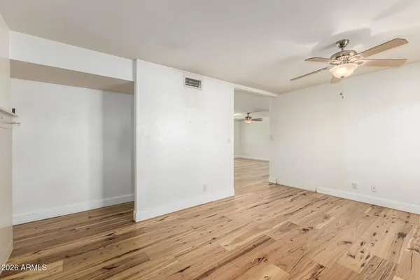 an empty room with wooden floor and fan