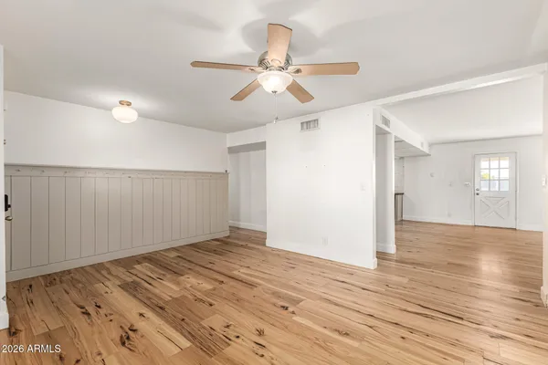an empty room with wooden floor fan and windows