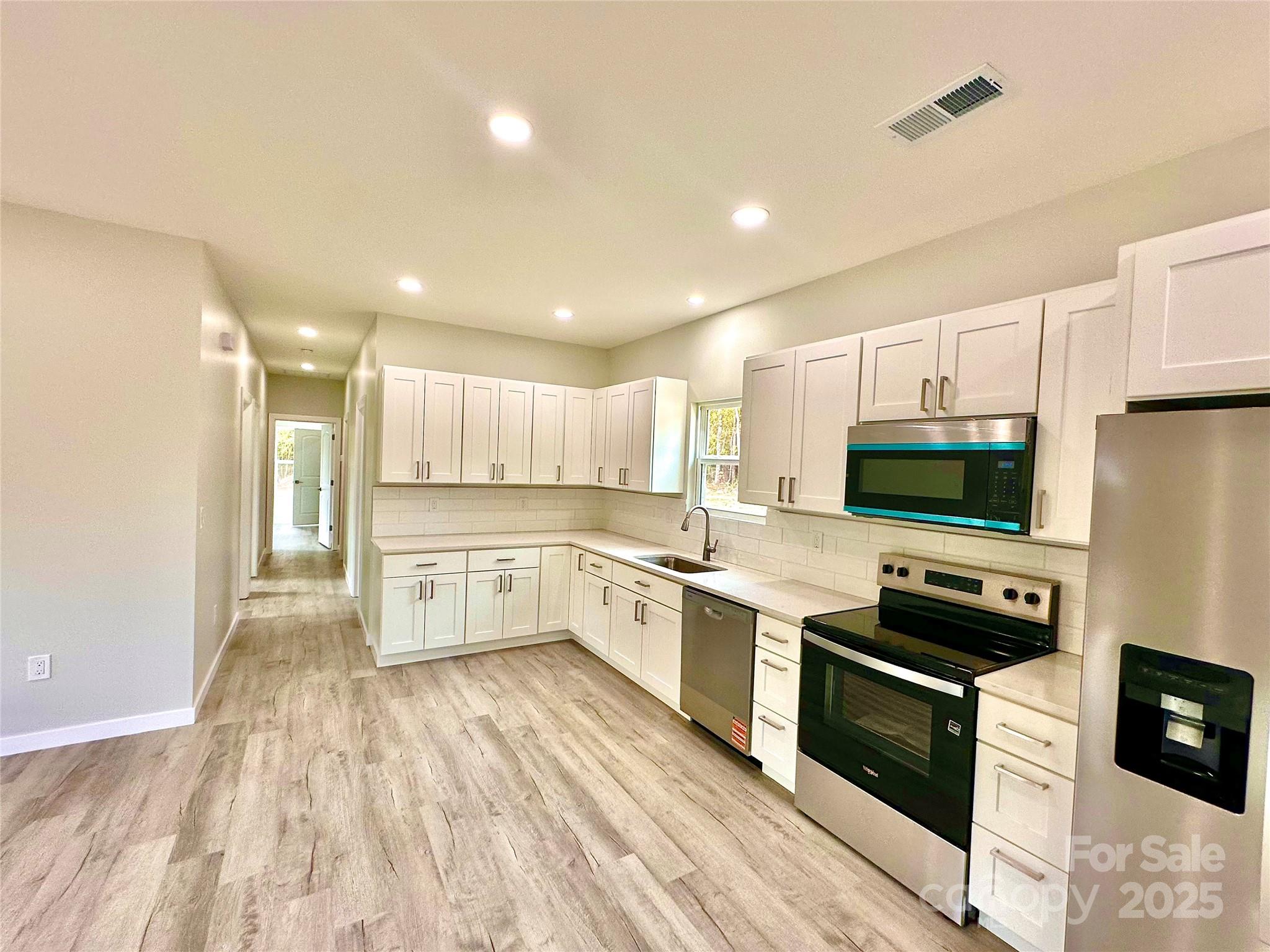 1171 Peach Orchard Road Jefferson, SC 29718 - Photo 7 of 30 a kitchen with granite countertop a stove top oven a sink dishwasher and a refrigerator with wooden floor