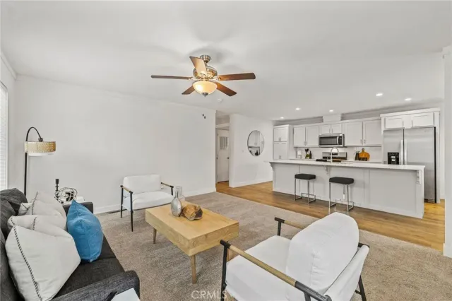 a living room with furniture kitchen view and a chandelier