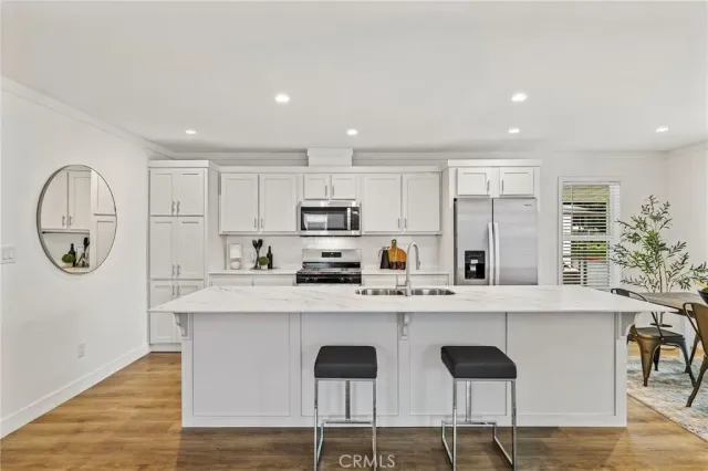 a kitchen with stainless steel appliances granite countertop a table chairs sink and cabinets