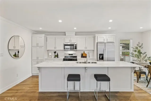 a kitchen with stainless steel appliances granite countertop a table chairs sink and cabinets