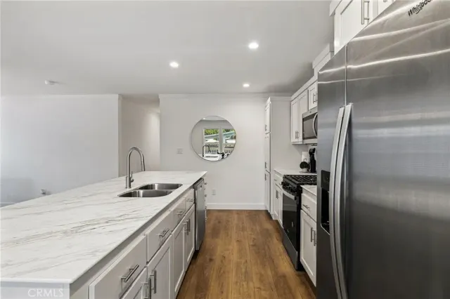 a kitchen with granite countertop stainless steel appliances a stove top oven a refrigerator a sink and dishwasher