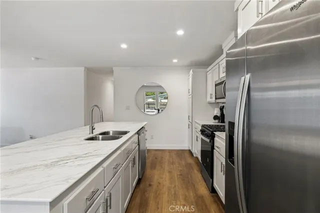 a kitchen with granite countertop stainless steel appliances a stove top oven a refrigerator a sink and dishwasher