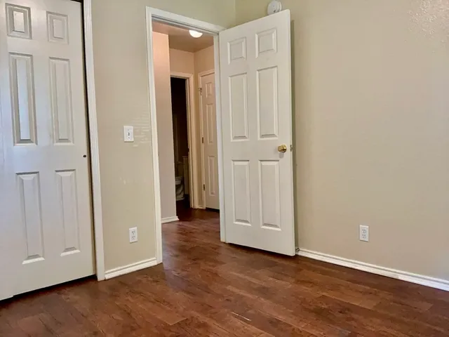 an empty room with wooden floor and closet area