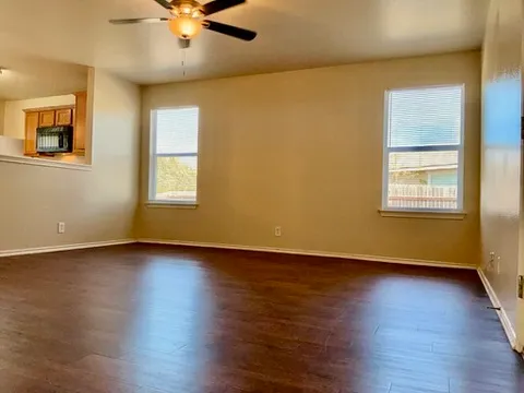 a view of an empty room with wooden floor and a window