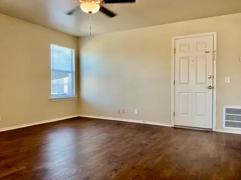 a view of an empty room with a window and wooden floor